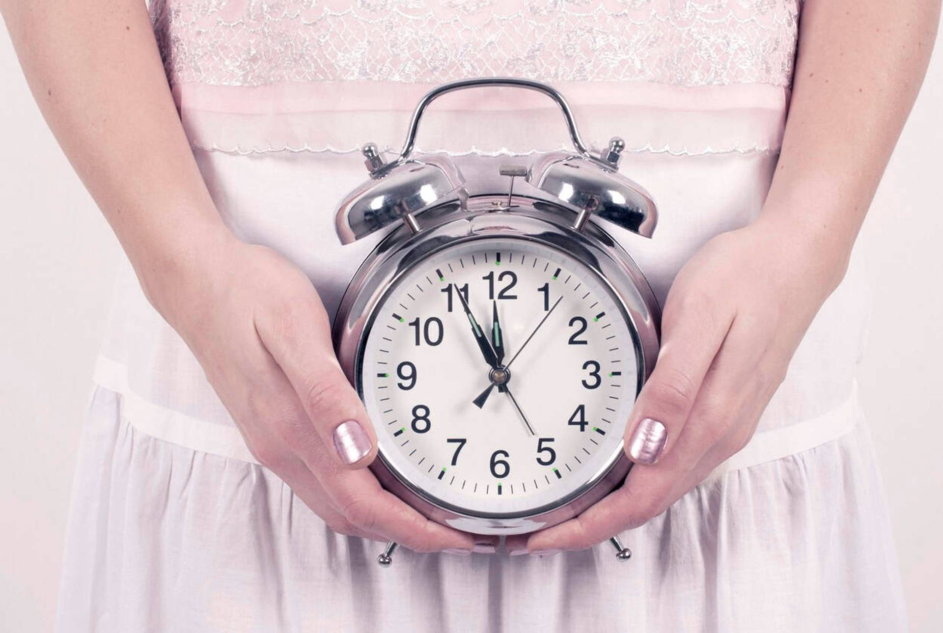Personne tenant une horloge devant le ventre.