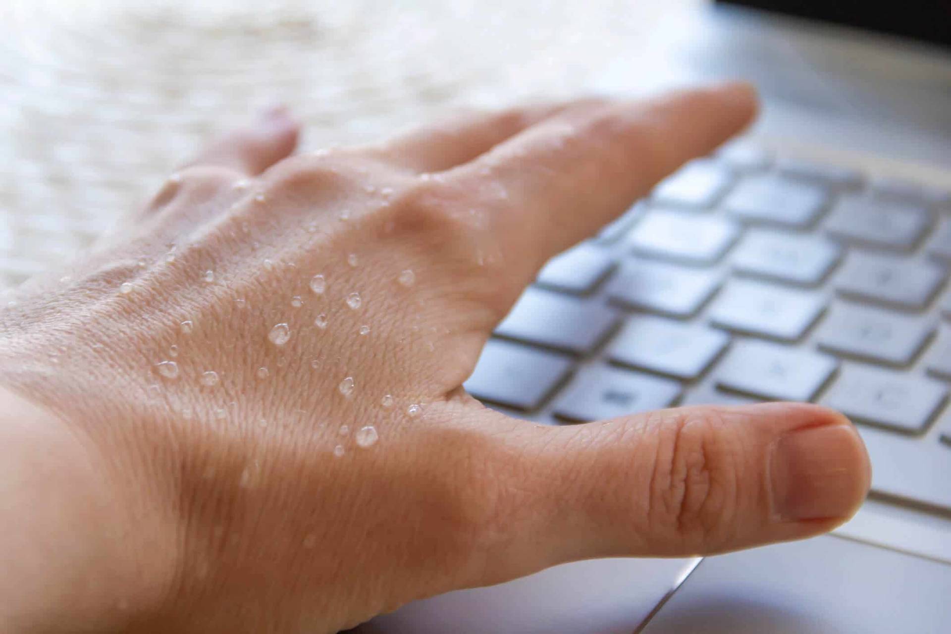 Gros plan d’une main humide sur un clavier.
