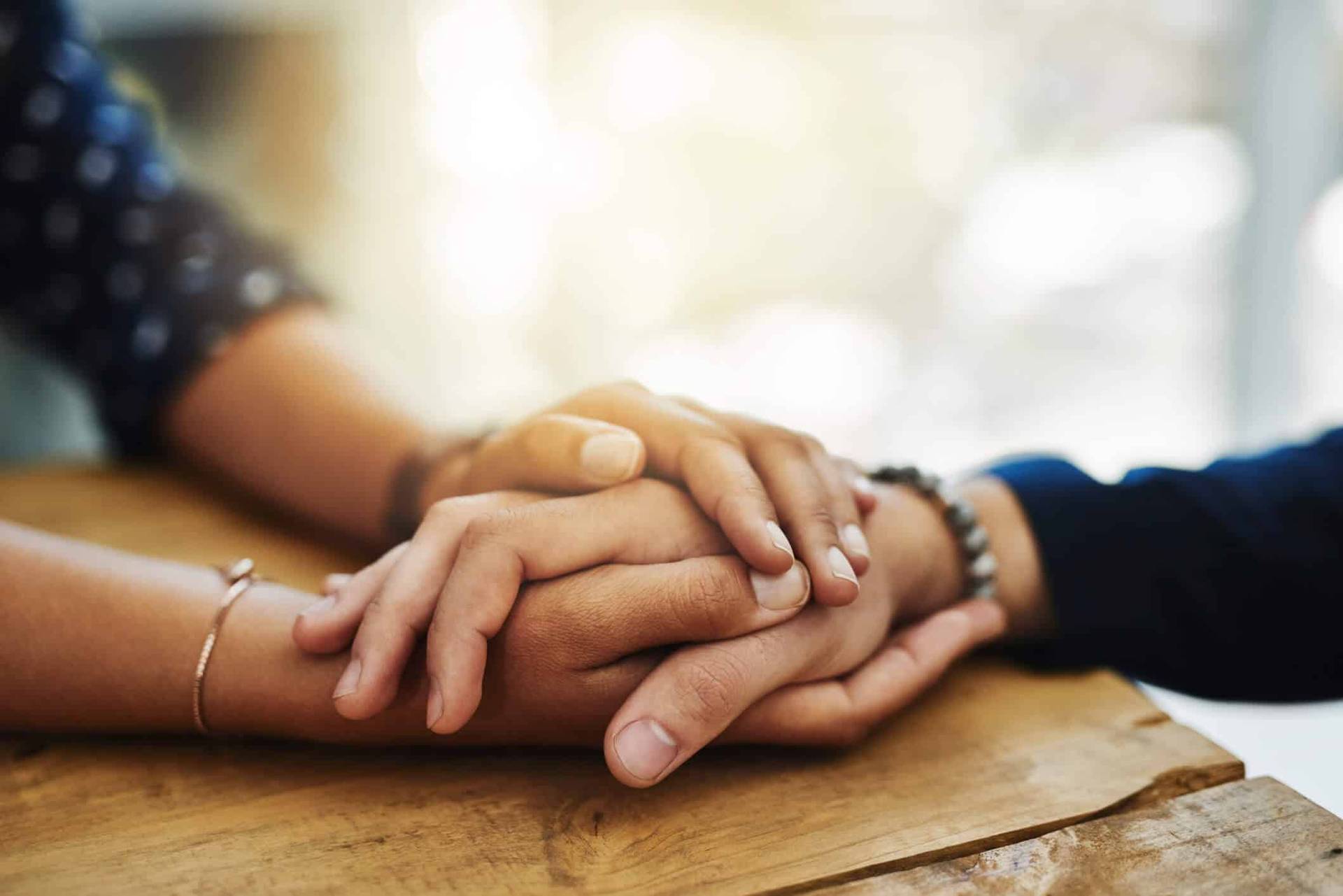 Deux personnes se tiennent les mains sur une table.