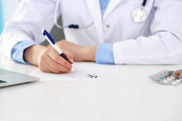 Médecin qui rédige un certificat médical sur son bureau