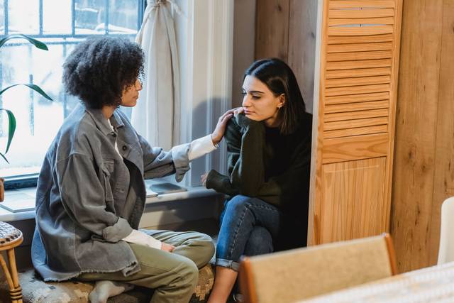 Deux amies partageant un moment réconfortant à la maison, illustrant l'empathie et le soutien
