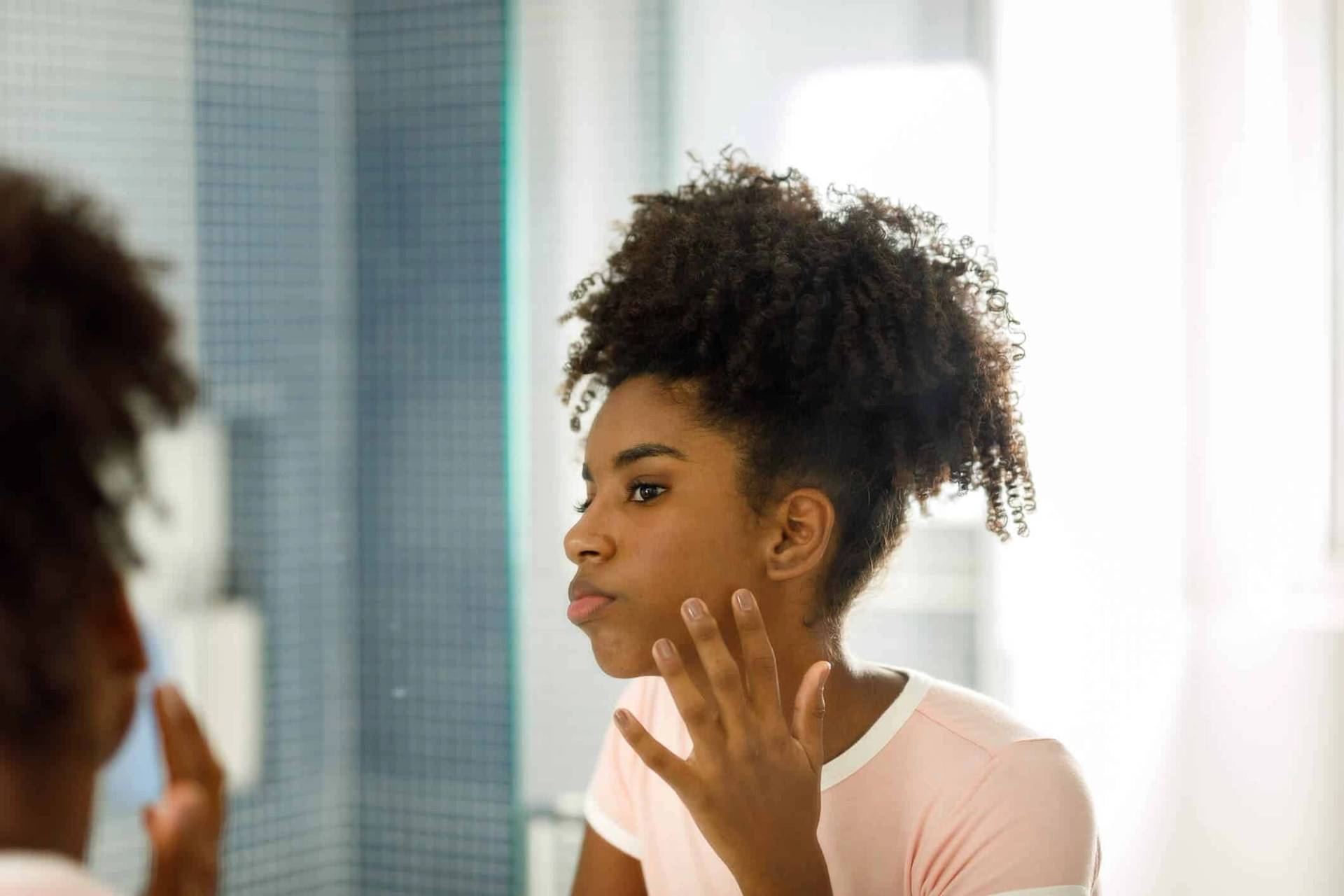 Femme observant son visage dans un miroir.