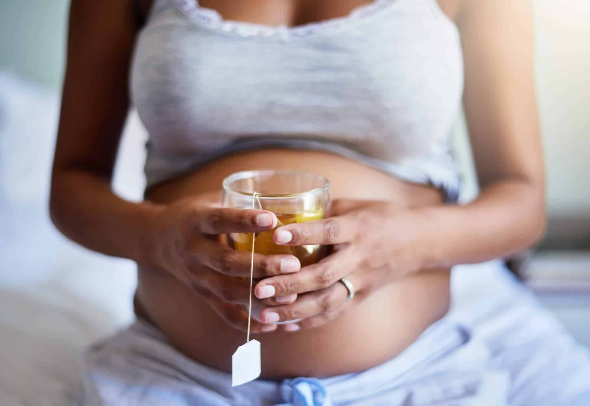 Femme enceinte tenant une tasse.