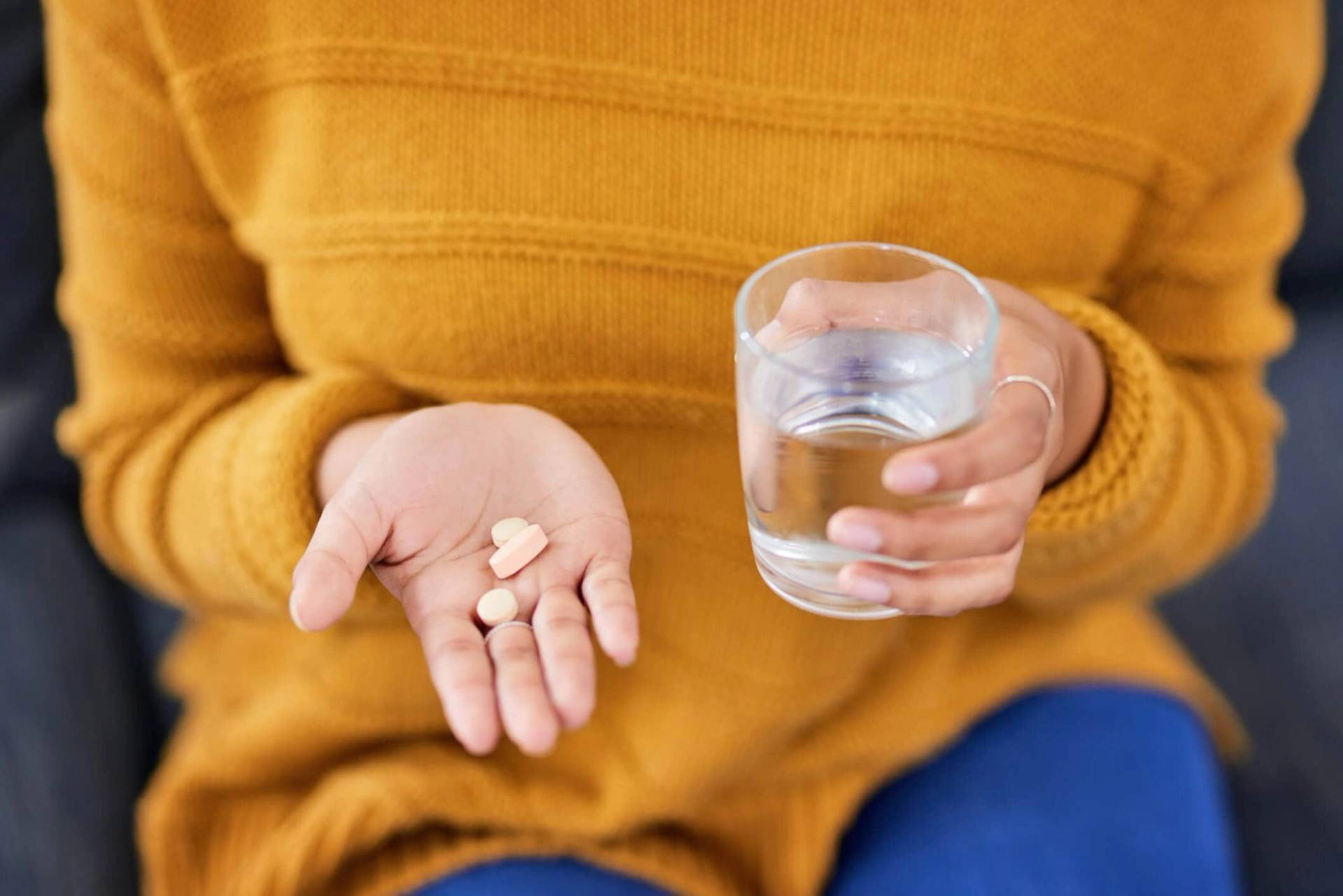 Femme tenant des médicaments et un verre d’eau.