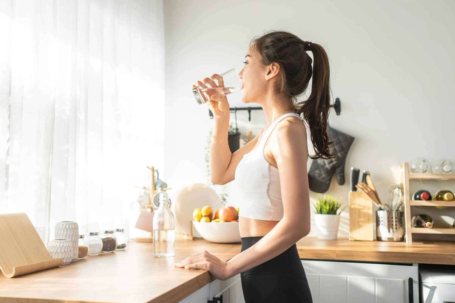 Femme buvant de l’eau dans une cuisine.