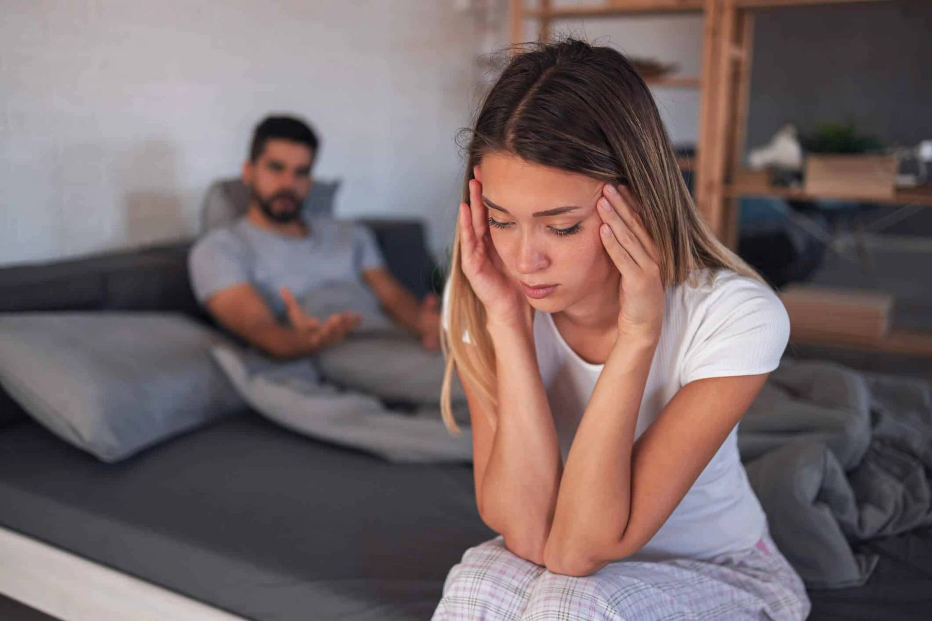 Femme préoccupée au premier plan, homme utilisant un téléphone derrière elle.