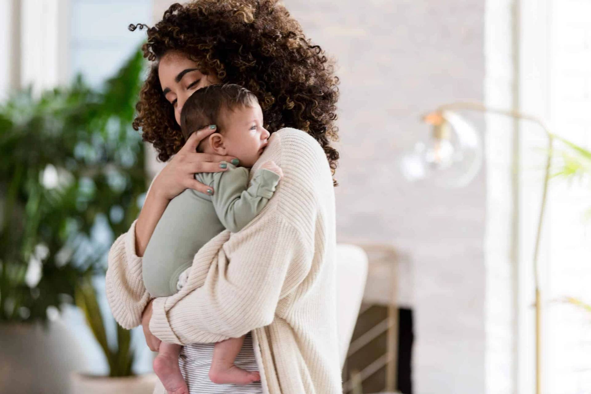 Adulte portant un bébé contre son épaule.