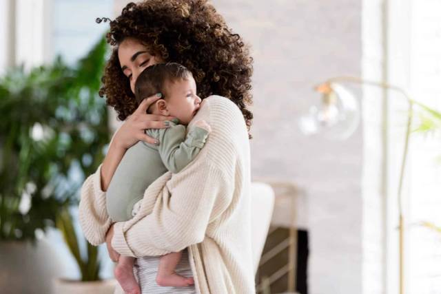 Adulte portant un bébé contre son épaule.