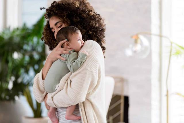 Adulte portant un bébé contre son épaule.