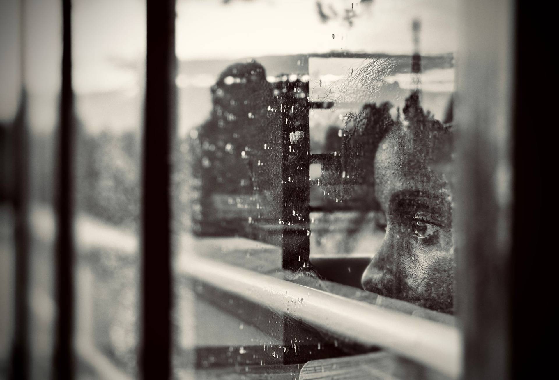 Un enfant, le regard perdu dans ses pensées, regarde à travers une fenêtre ruisselante de pluie