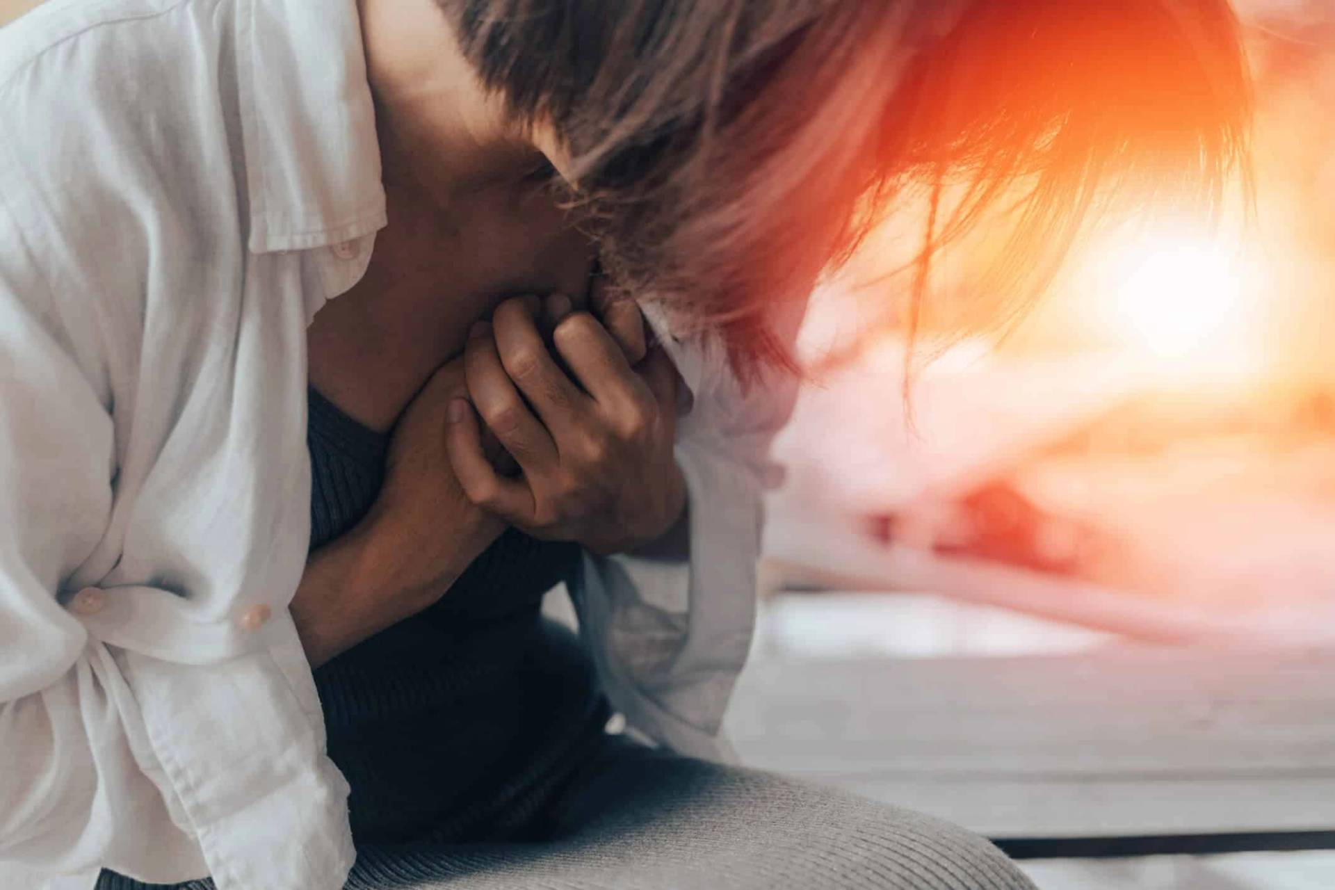 Homme se tenant la poitrine, assis près d’une fenêtre.