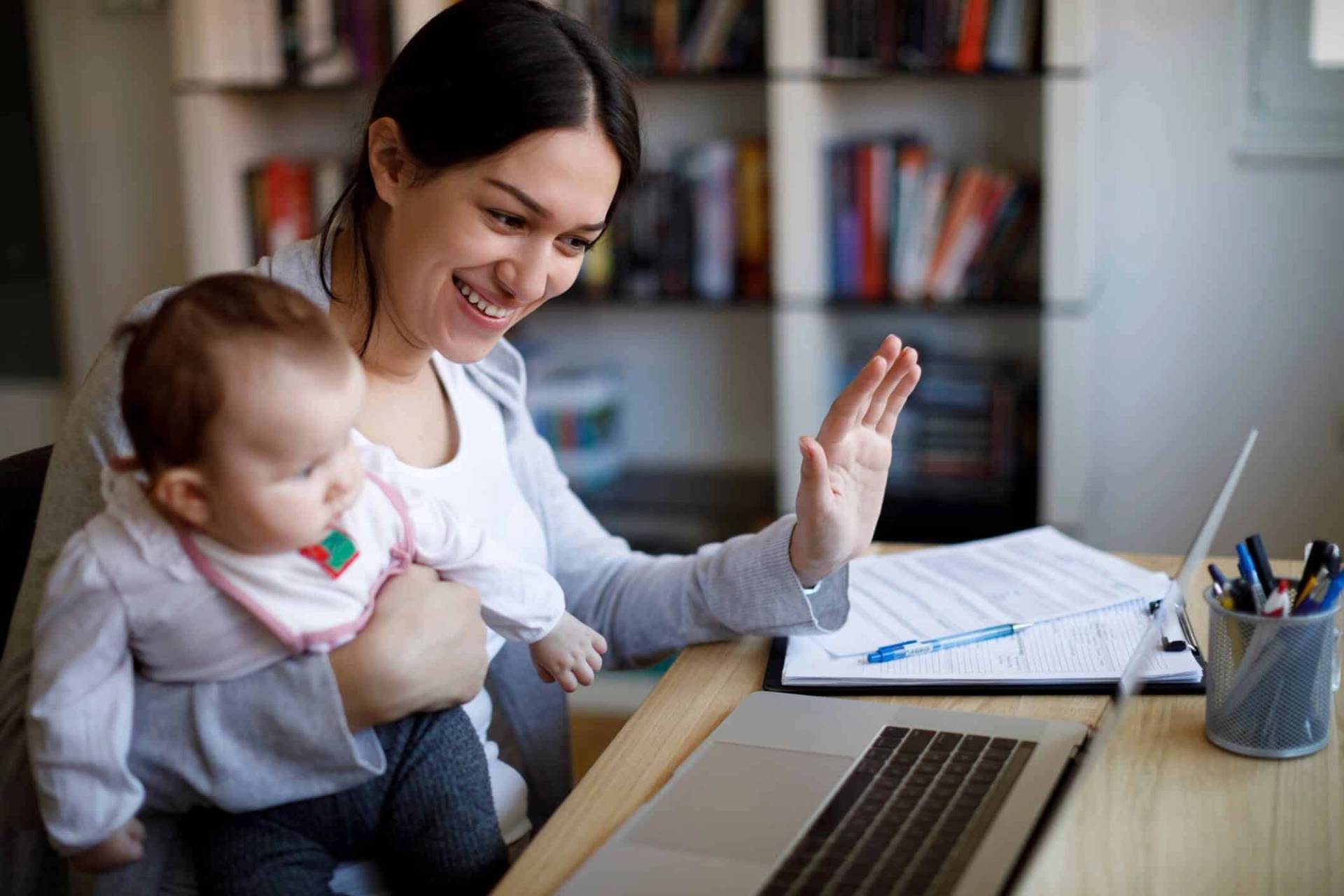 Adulte avec un bébé faisant un signe à un ordinateur.