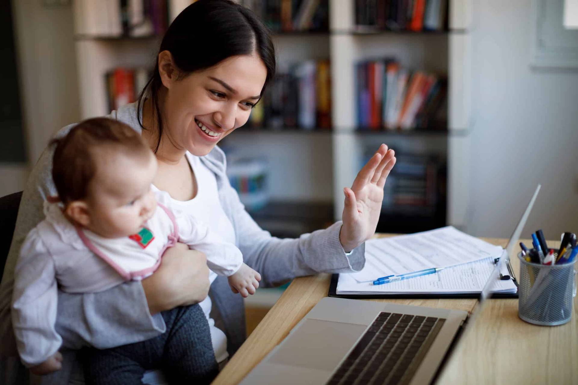 Adulte avec un bébé faisant un signe à un ordinateur.
