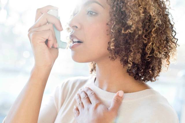 Femme utilisant un inhalateur.