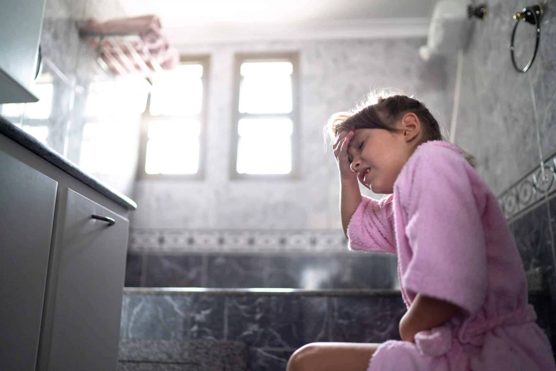 Enfant en peignoir assis aux toilettes.