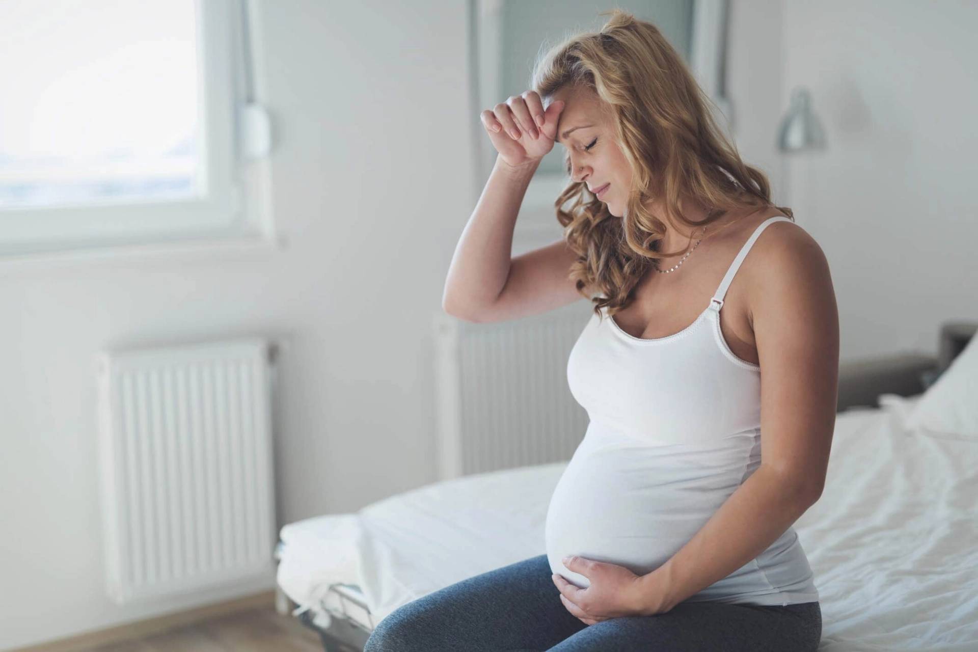 Femme enceinte posant une main sur son front.