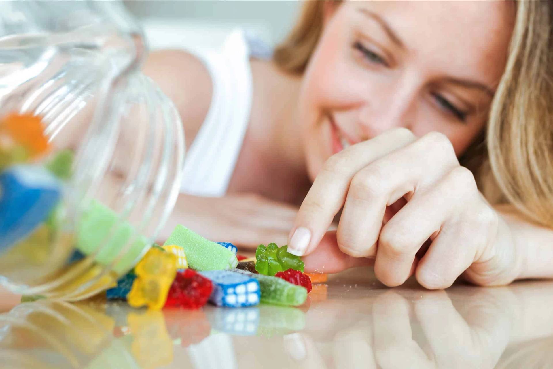 Femme choisissant des bonbons dans un bocal.