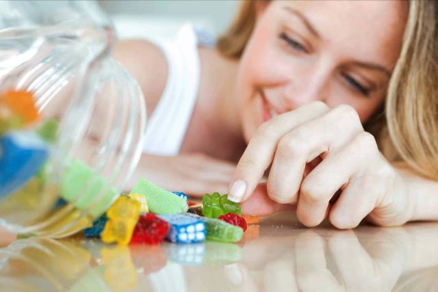 Femme choisissant des bonbons dans un bocal.