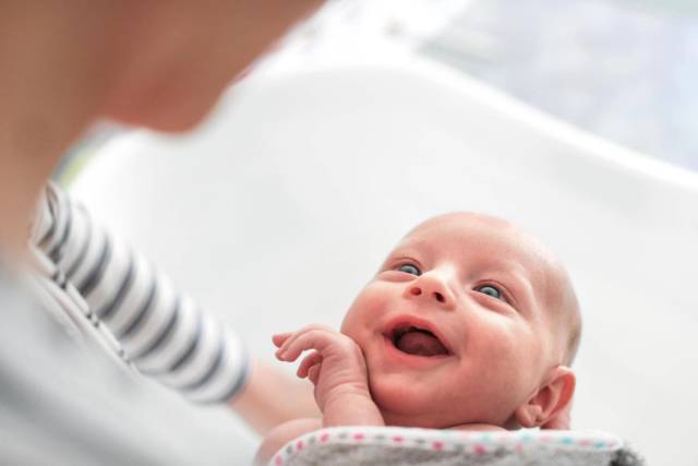 Adulte tenant un bébé souriant.