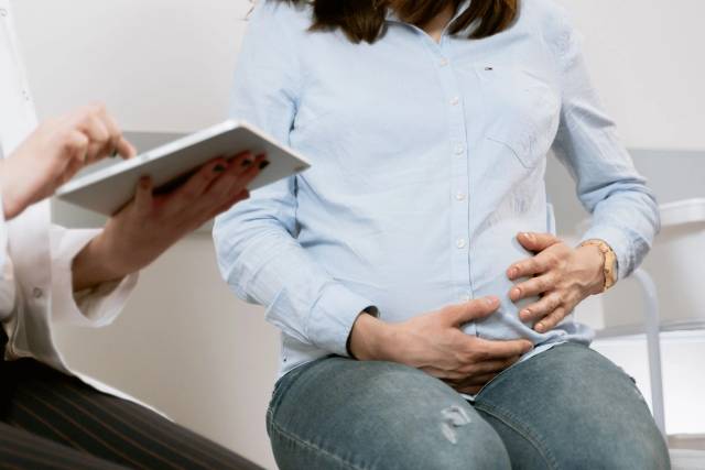 Femme enceinte assistant à une consultation médicale, illustrant l'interaction entre le médecin et le patient