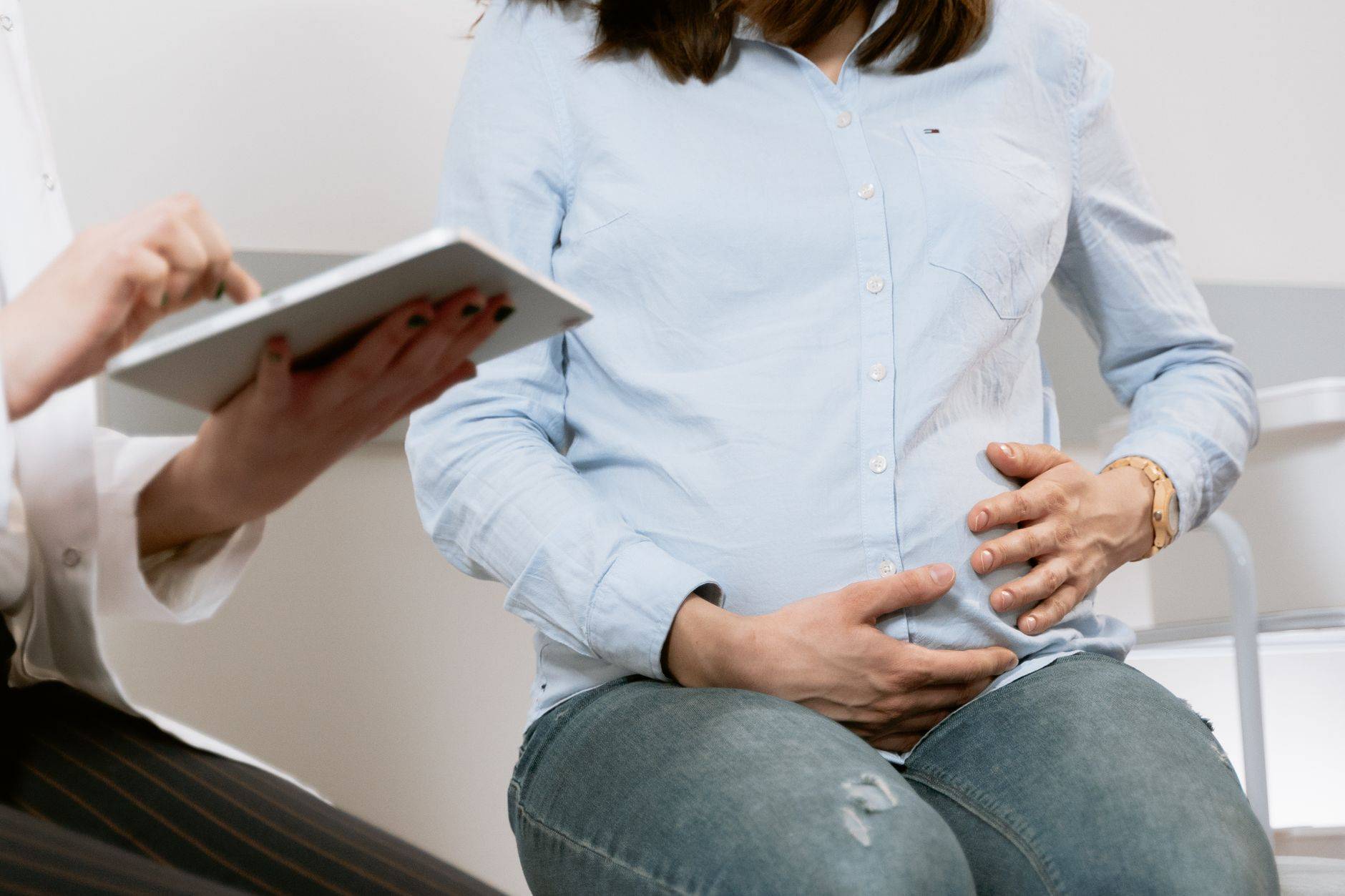 Femme enceinte assistant à une consultation médicale, illustrant l'interaction entre le médecin et le patient