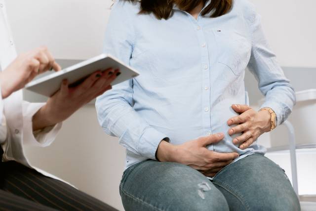 Femme enceinte assistant à une consultation médicale, illustrant l'interaction entre le médecin et le patient