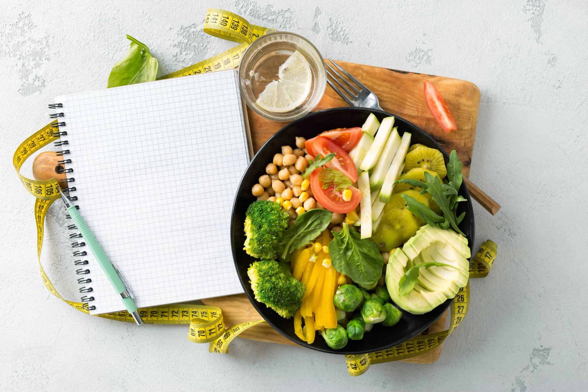 Salade et aliments frais à côté d’un carnet et d’un mètre ruban.