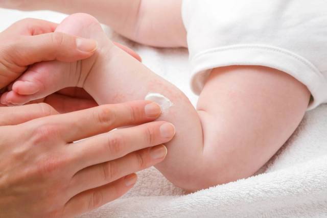 Application de crème sur le bras d’un bébé.