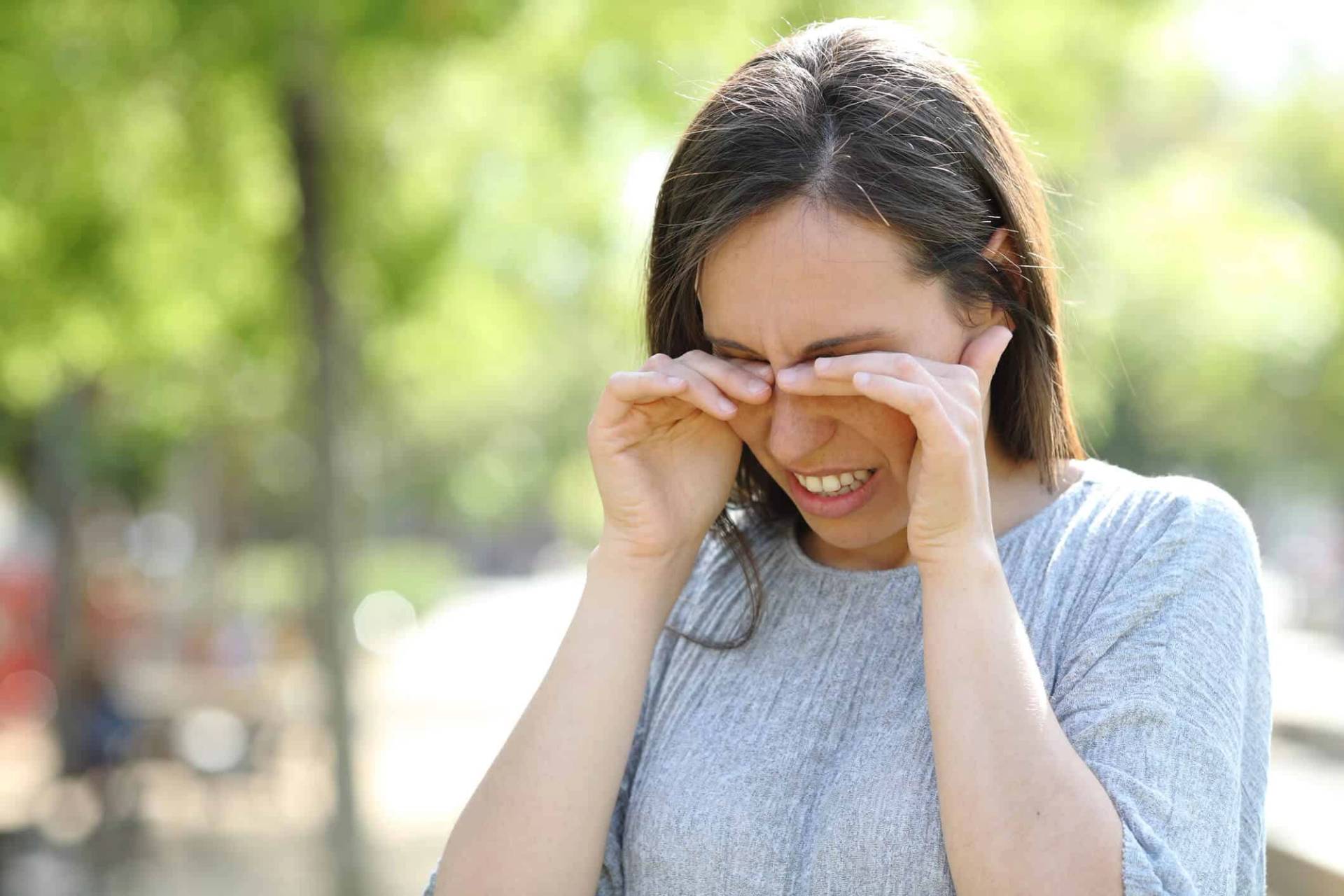 Femme se frottant les yeux dehors.