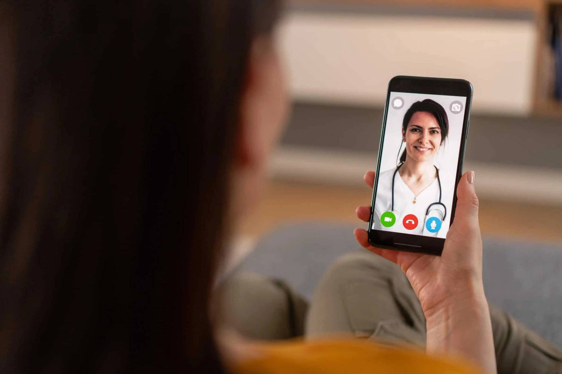 Personne tenant un téléphone montrant une professionnelle en vidéo.