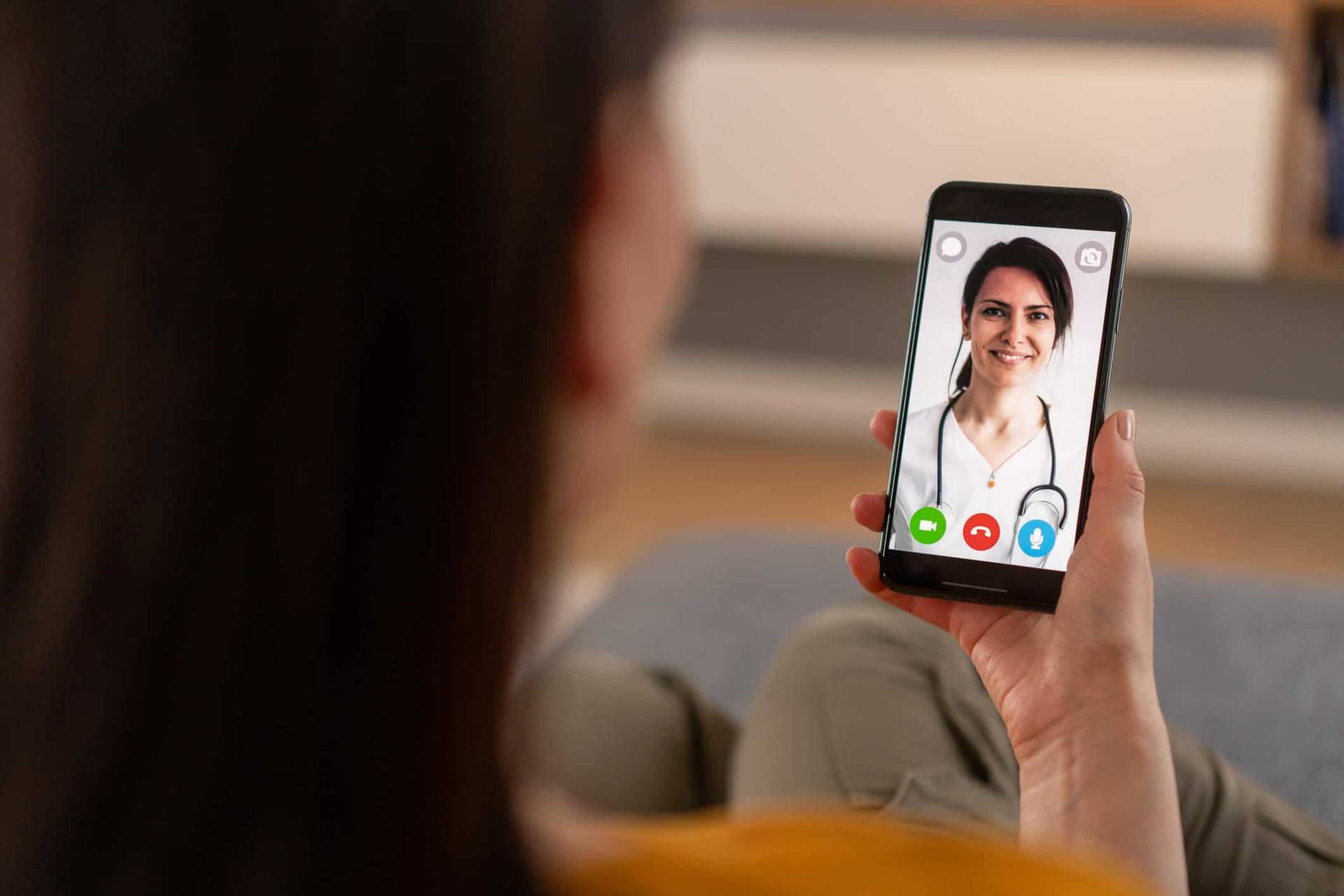 Personne tenant un téléphone montrant une professionnelle en vidéo.