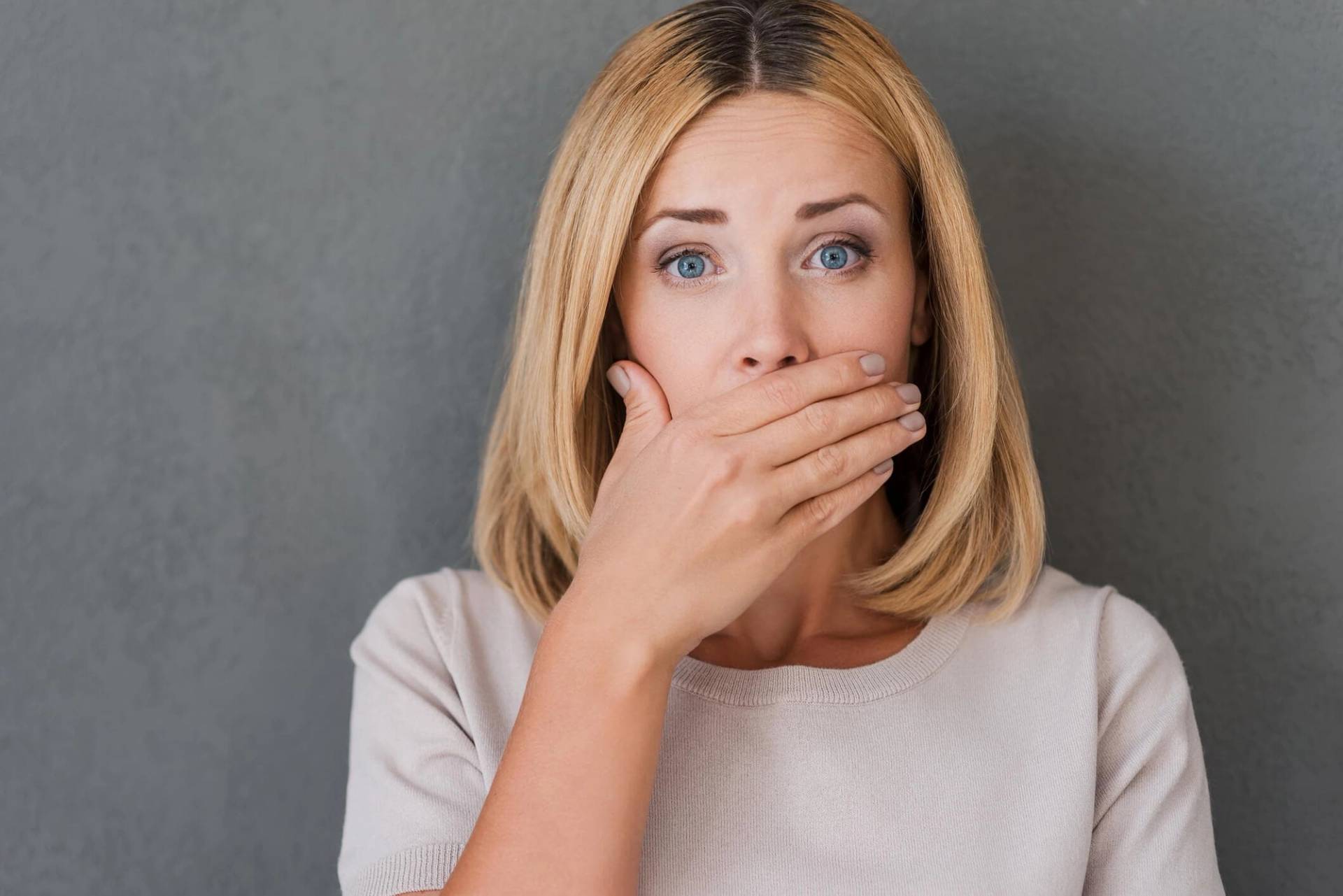 Femme portant la main devant sa bouche.