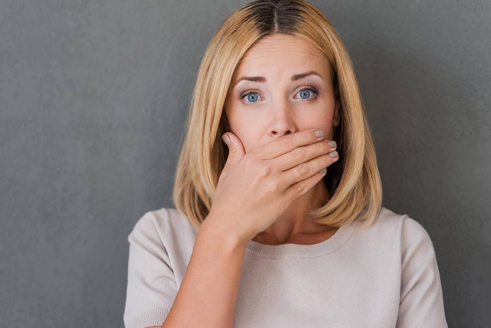 Femme portant la main devant sa bouche.