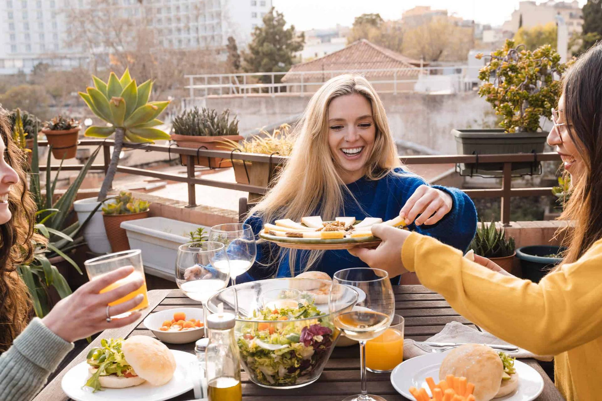 Groupe partageant un repas et des boissons sur une terrasse.