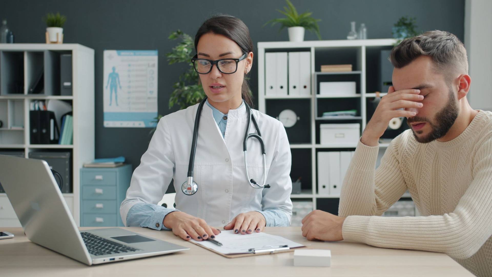 Un professionnel de santé discute avec un patient dans son cabinet médical. Le stress et l'inquiétude sont
