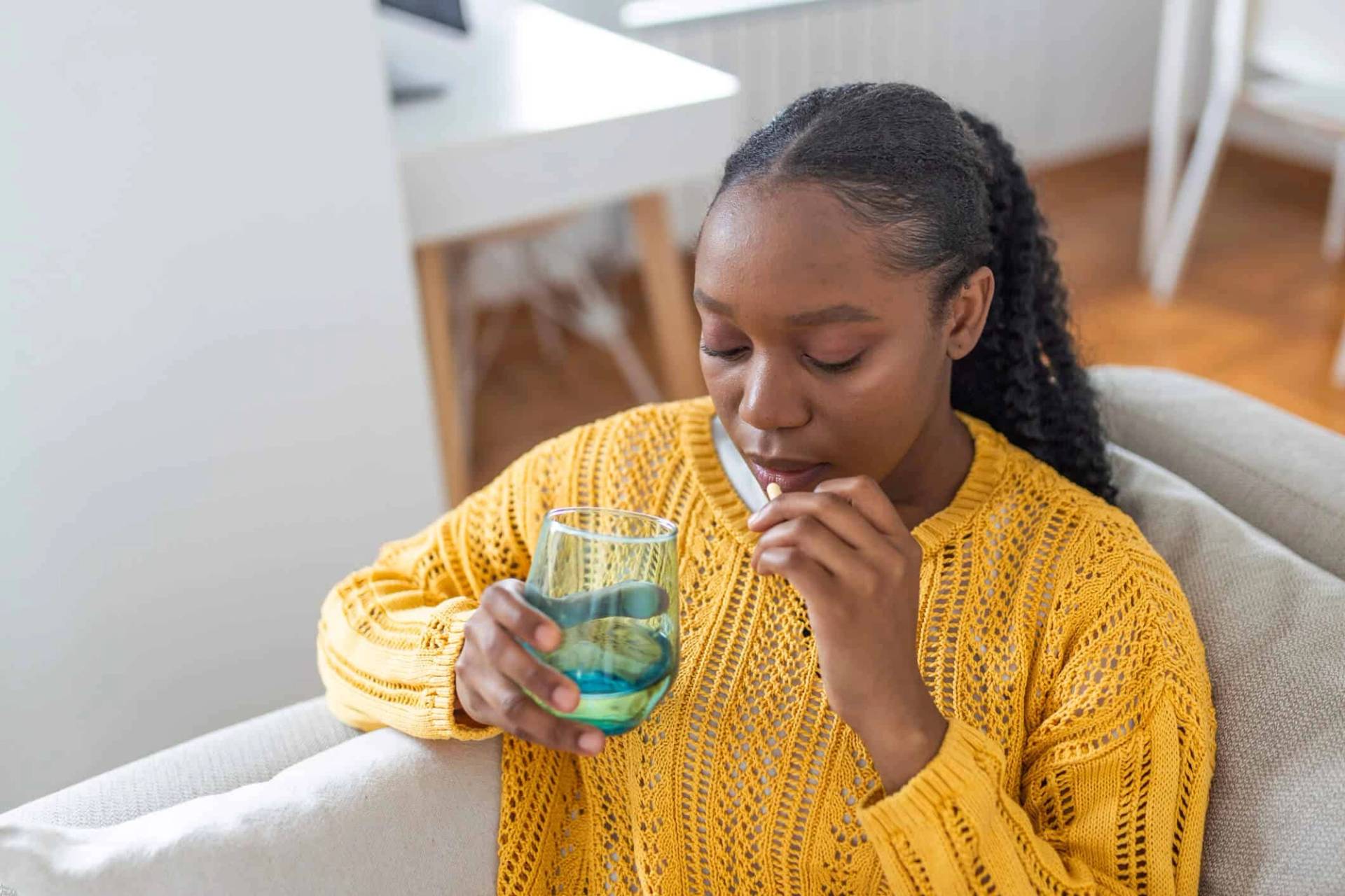 Une femme prend un comprimé avec un verre d'eau.