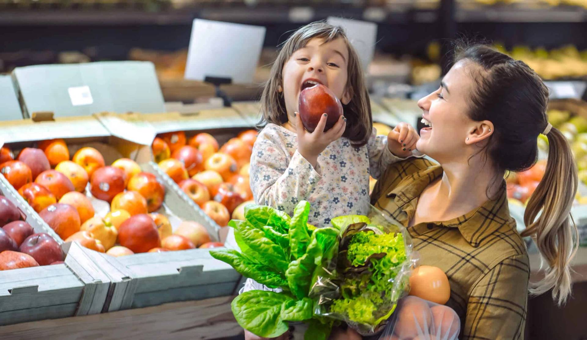 Adulte et enfant dans un rayon de fruits et légumes.
