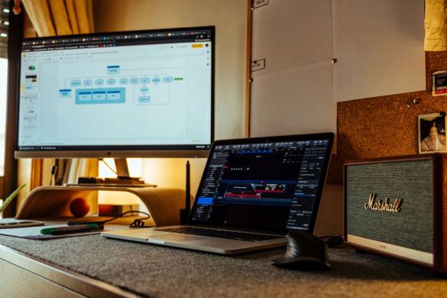 Bureau à domicile confortable avec ordinateur portable, grand moniteur et enceintes, idéal pour la productivité et