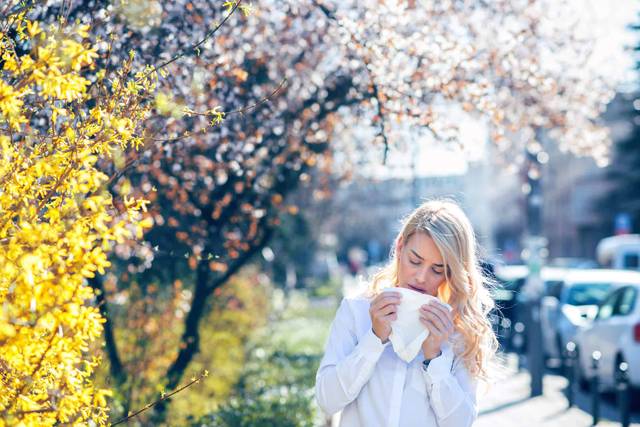 Une femme se mouche près d'arbres en fleurs.