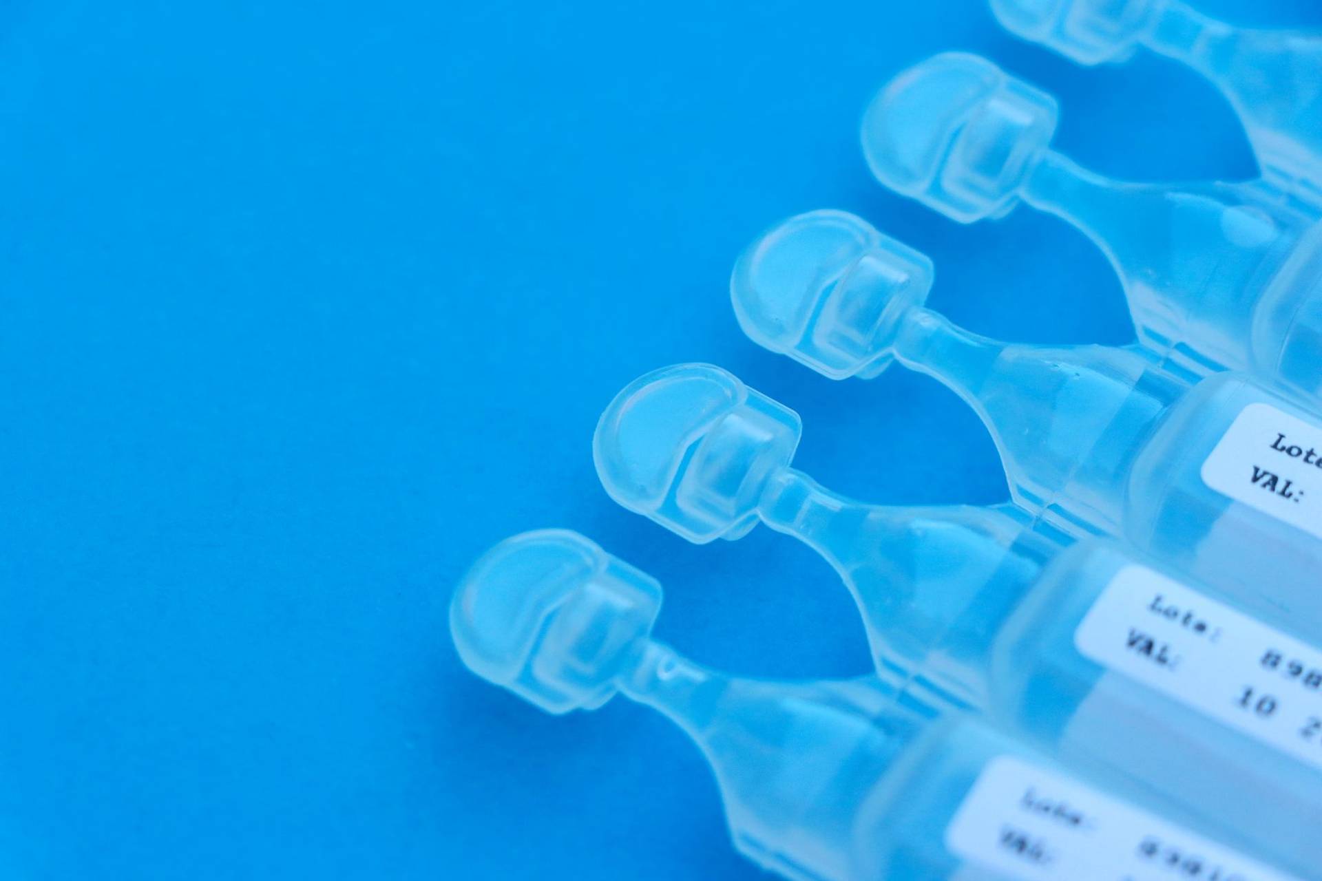 Rangée de dosettes en plastique transparent sur fond bleu.