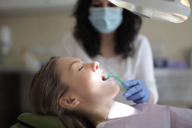 Un dentiste portant un équipement de protection examine les dents d'un patient dans une clinique