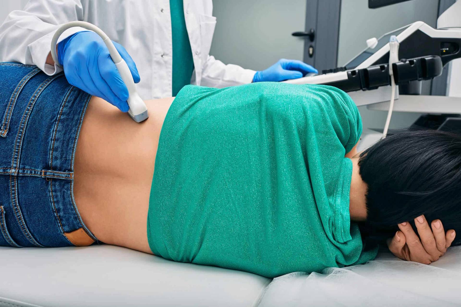Médecin réalisant une échographie abdominale sur une patiente allongée avec sonde échographique