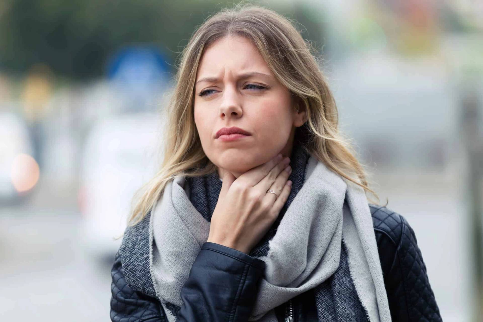 Une femme touche le côté de son cou dans la rue.