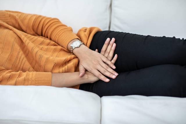Une personne allongée pose les mains sur son bas-ventre.
