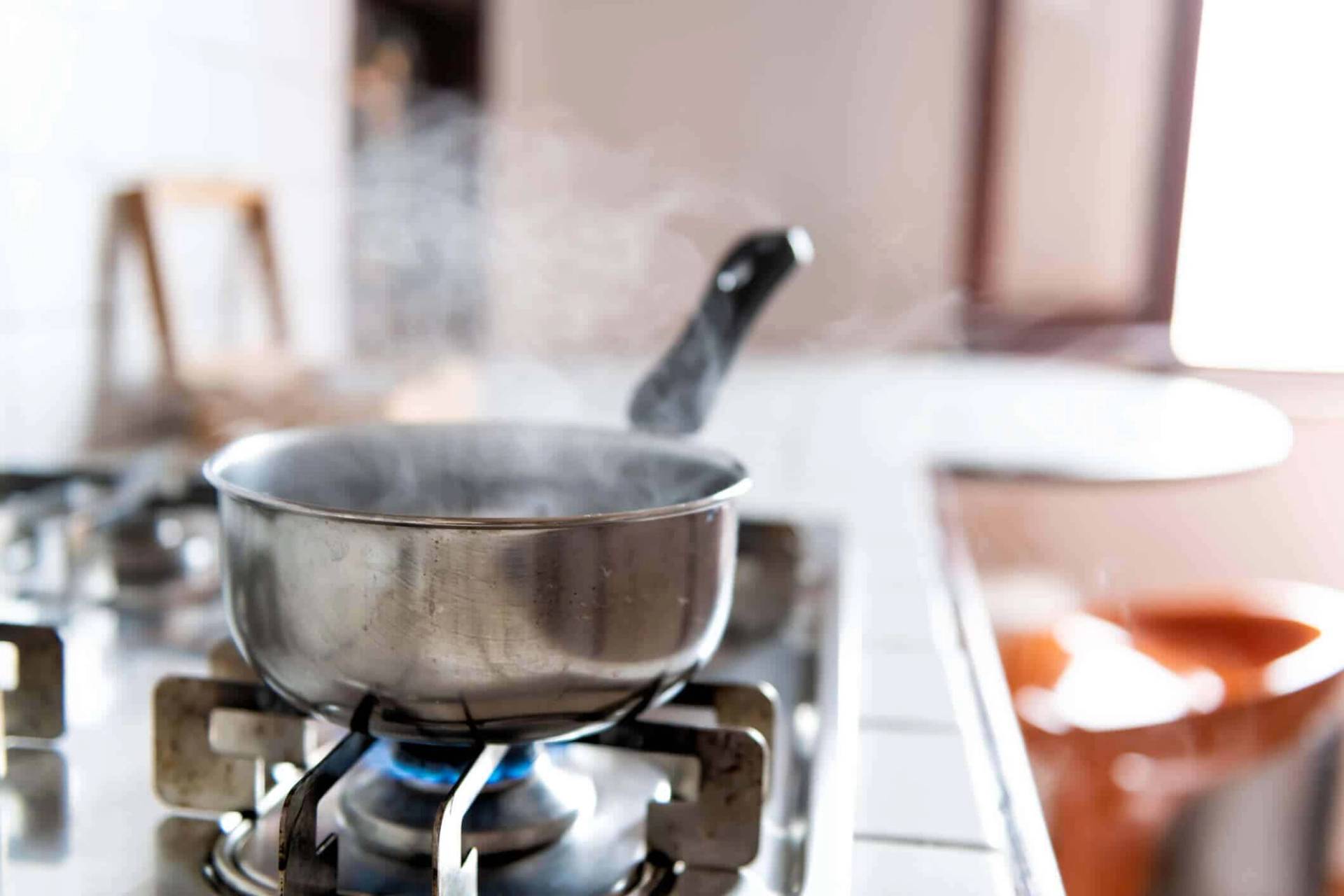 Une casserole chauffe sur la flamme d'une gazinière.