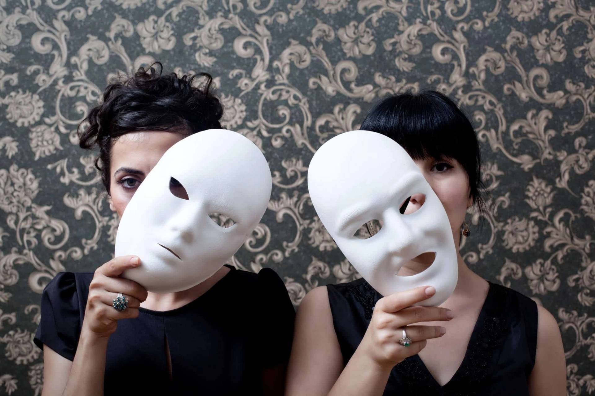 Deux personnes tiennent chacune un masque blanc devant leur visage.