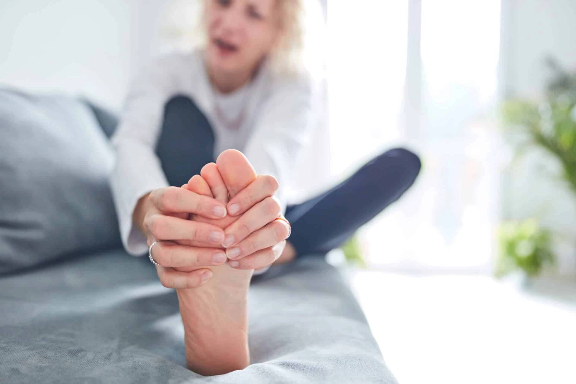 Une personne assise se masse le pied.