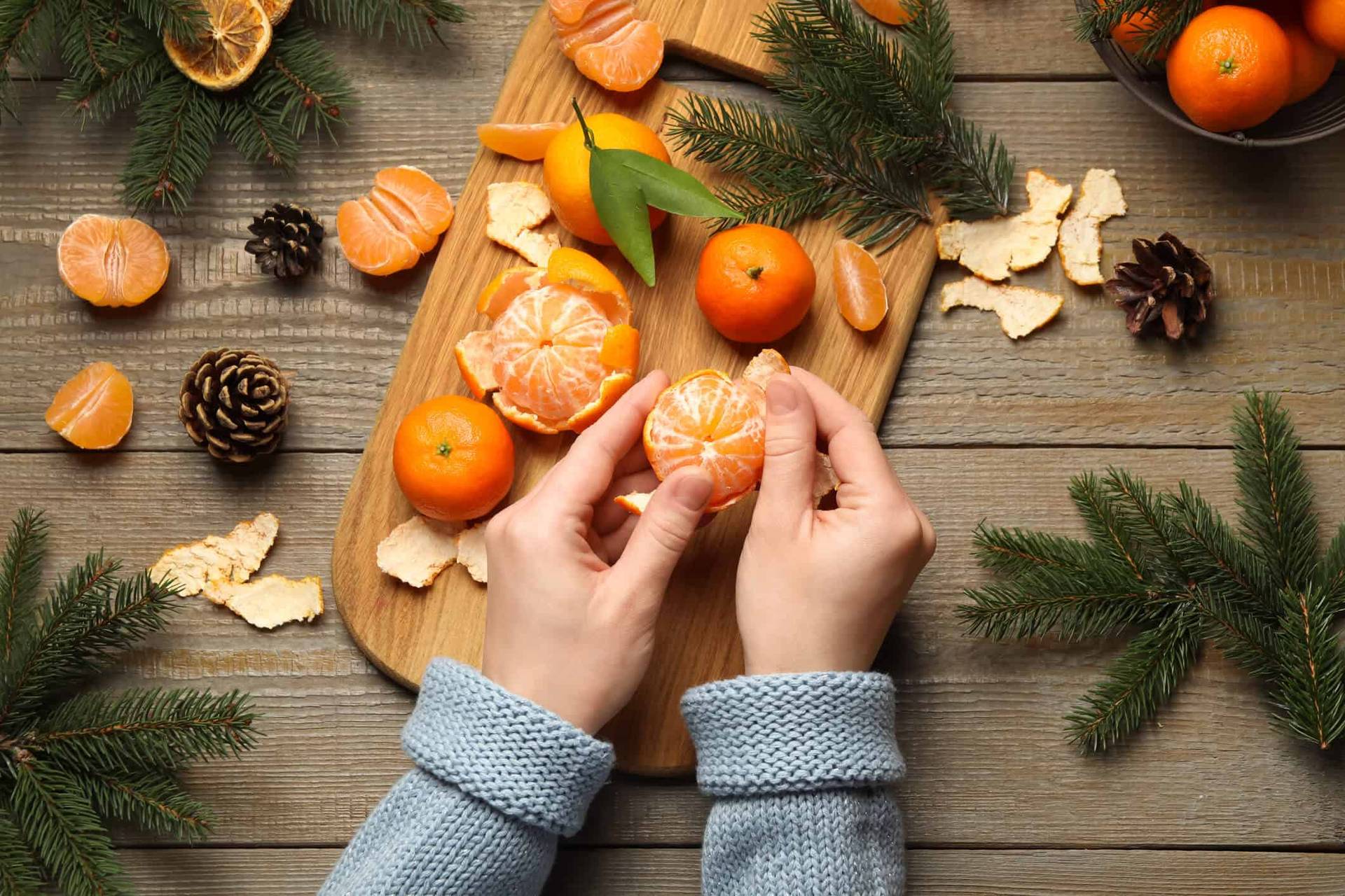 Mains épluchant une clémentine parmi des agrumes sur une table.