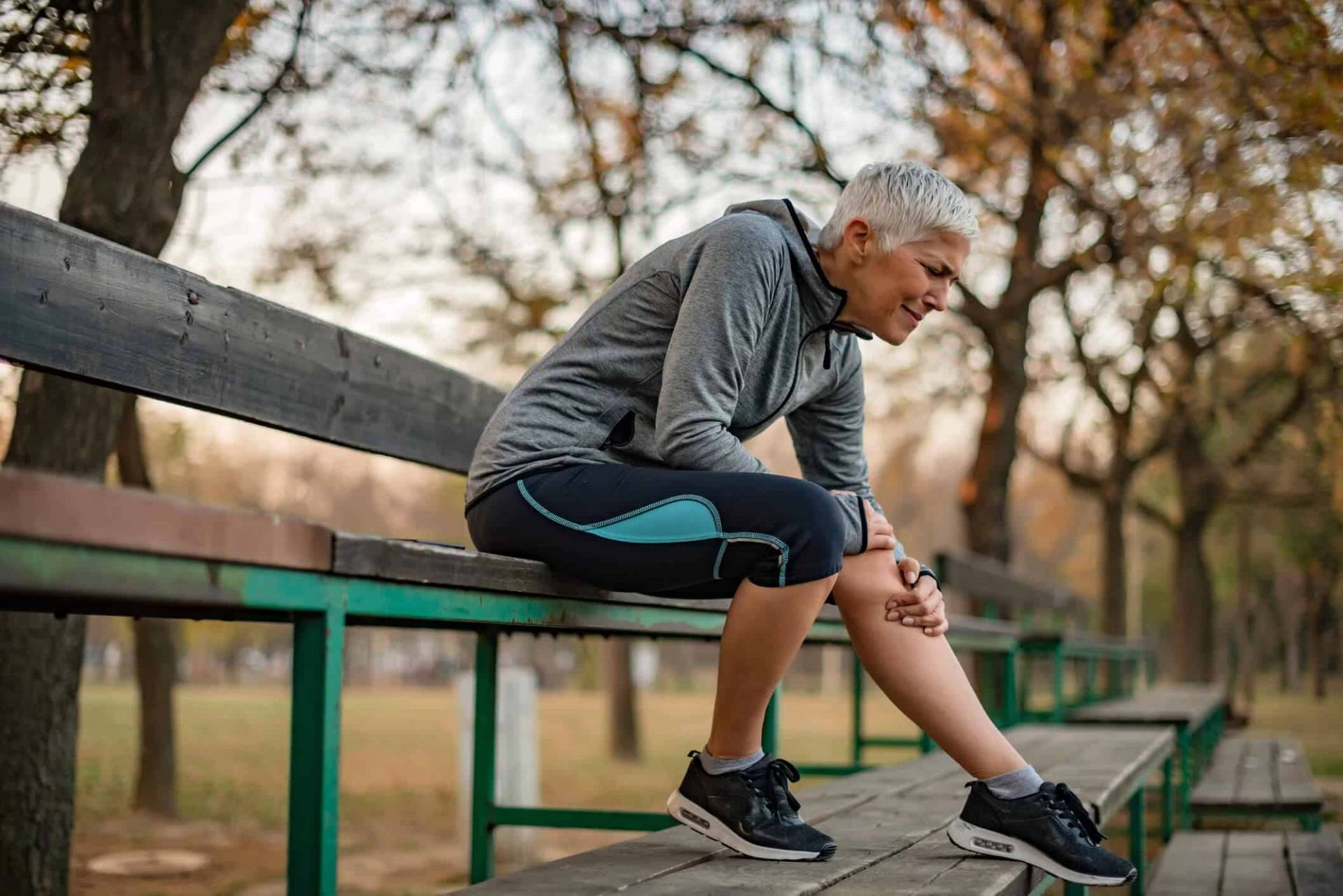 Un coureur assis sur un banc se tient le genou.