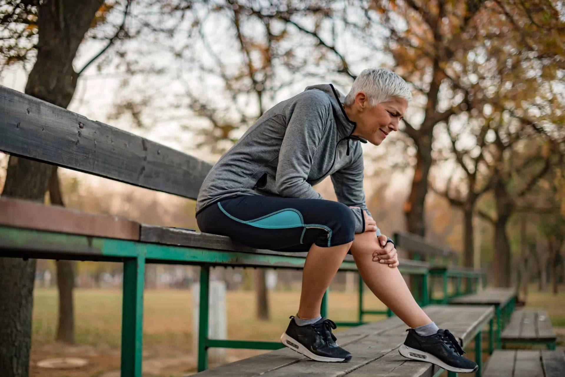 Un coureur assis sur un banc se tient le genou.